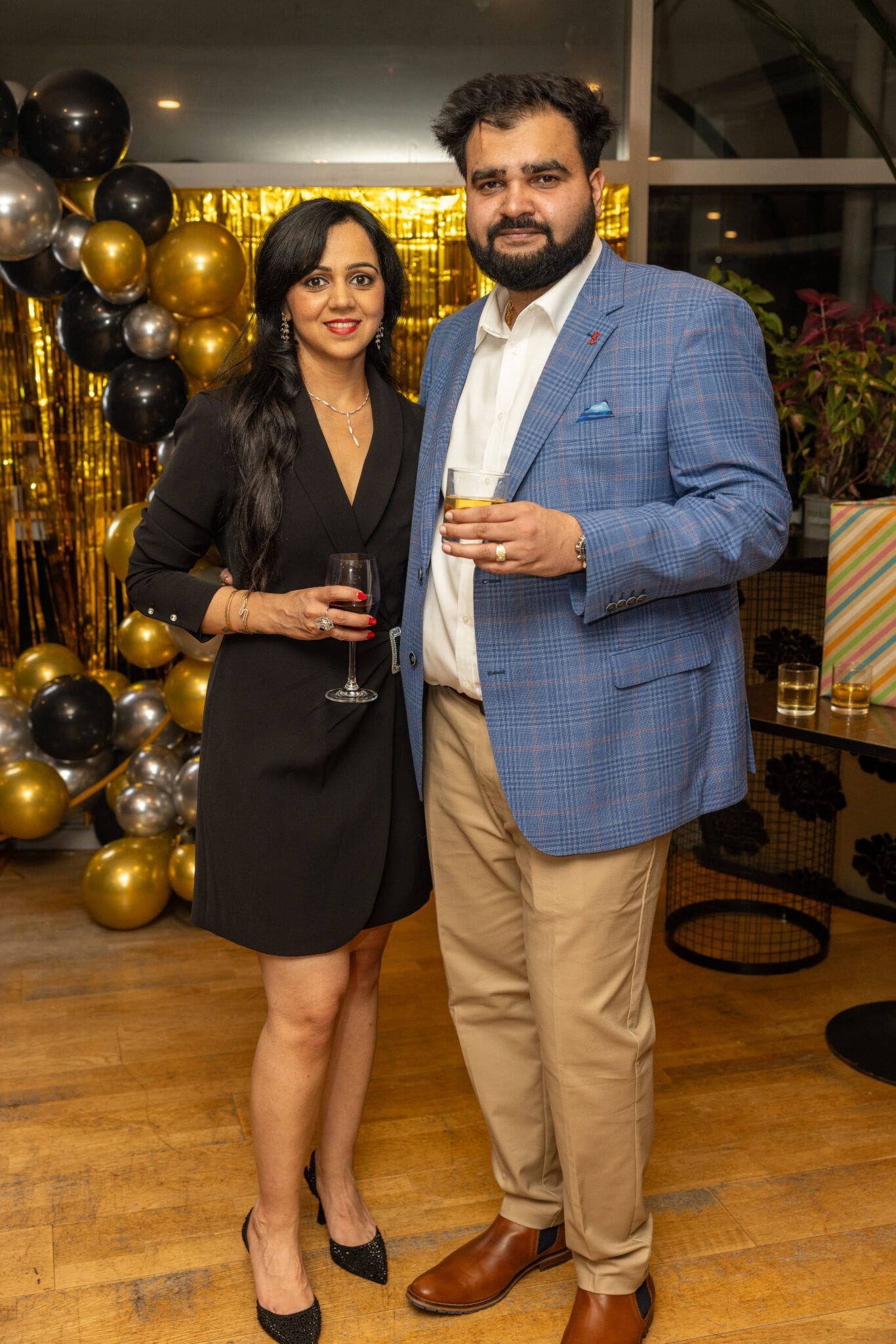 Guests posing in front of gold and black balloons at a Wellington evening function